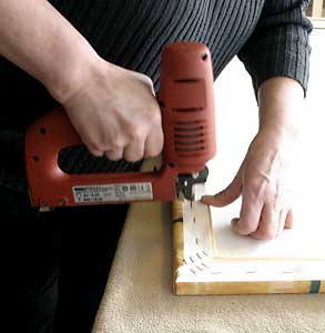 Hand stretching and affixing the canvas to the inner wooden frame.